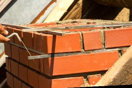 Jointing tool striking fresh mortar lines on red brick