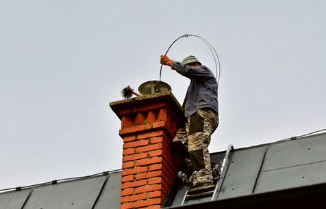 Sweep guiding a hoop brush into an orange brick chimney in Redondo Beach